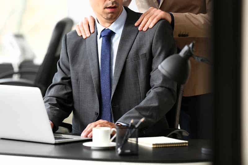 Hombre acosando a su colega masculino en la oficina