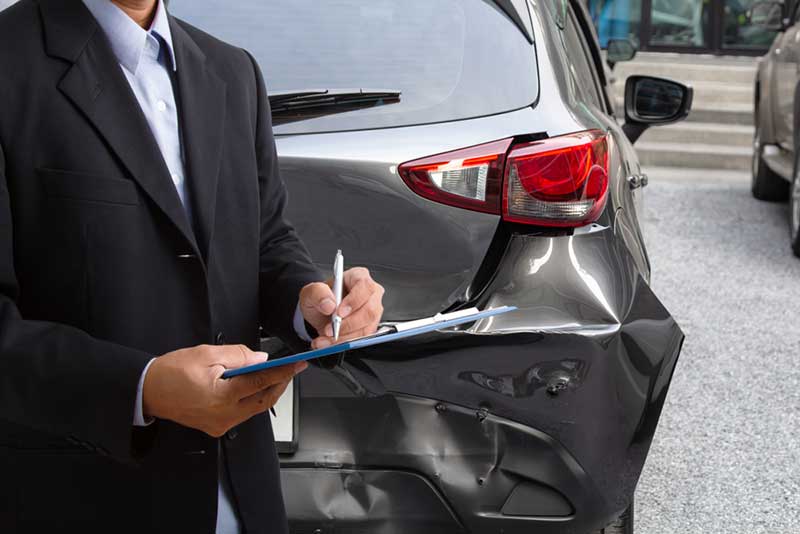 man holding a form standing next to a crashed car