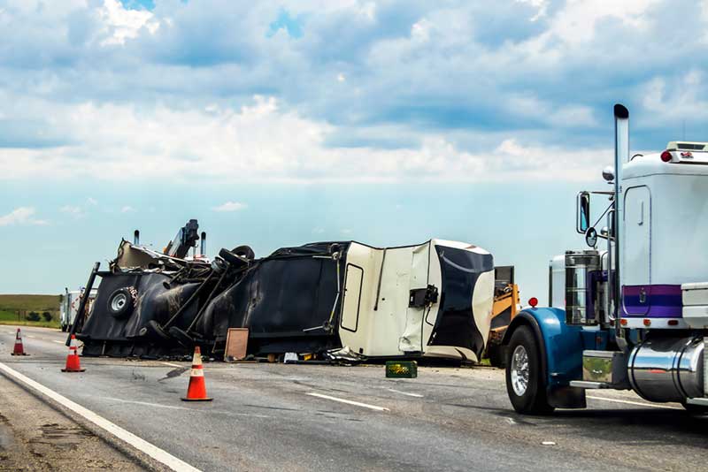 white truck flipped over on the side of the road