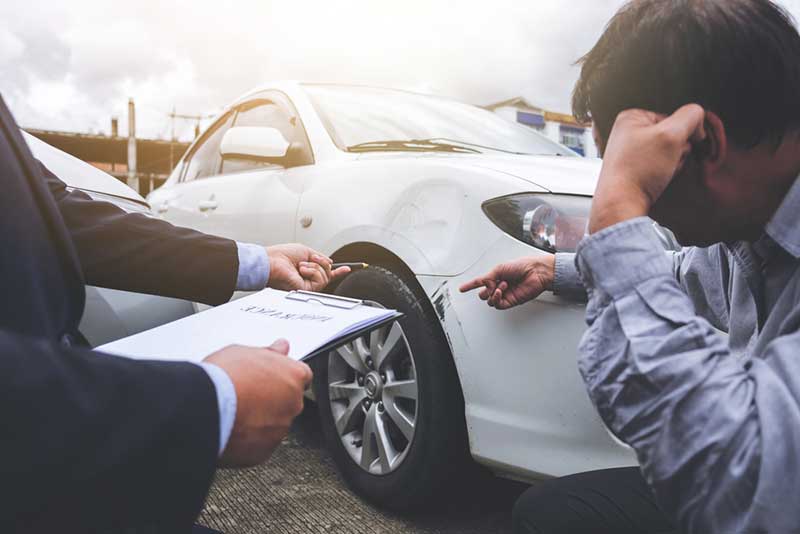 man examining damage in a car